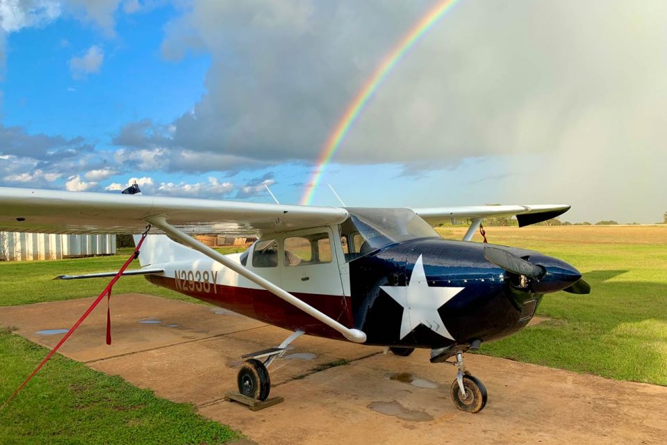 Small airplane with Texas flag paint scheme on a runway with a rainbow in the background