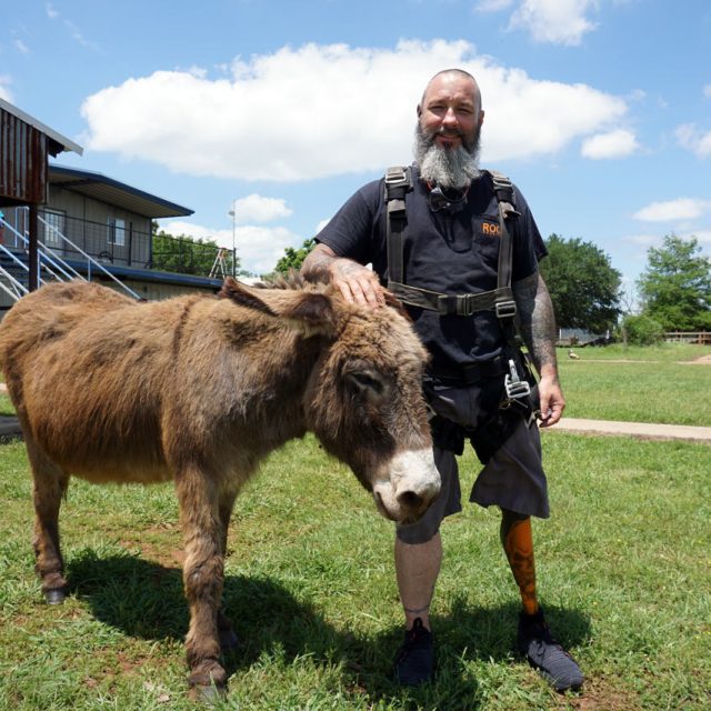 Male tandem skydiving student petting a donkey before his skydive at Texas Skydiving near Austin, TX