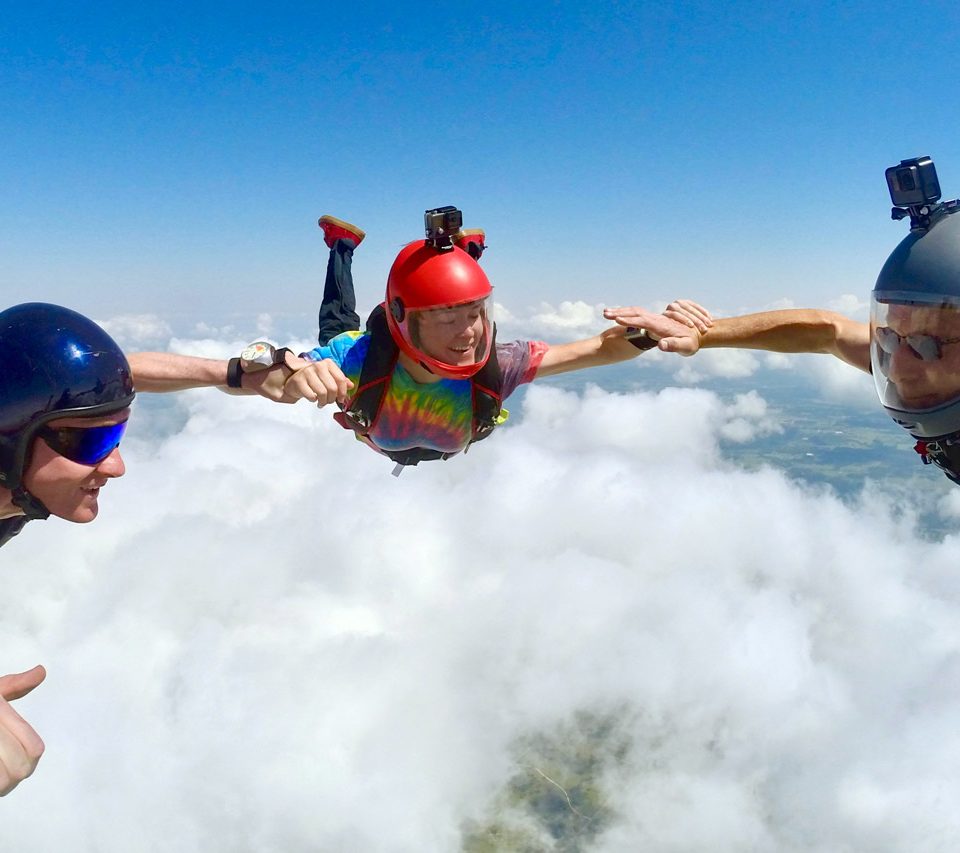 Licensed skydivers hold wrists during a formation skydive