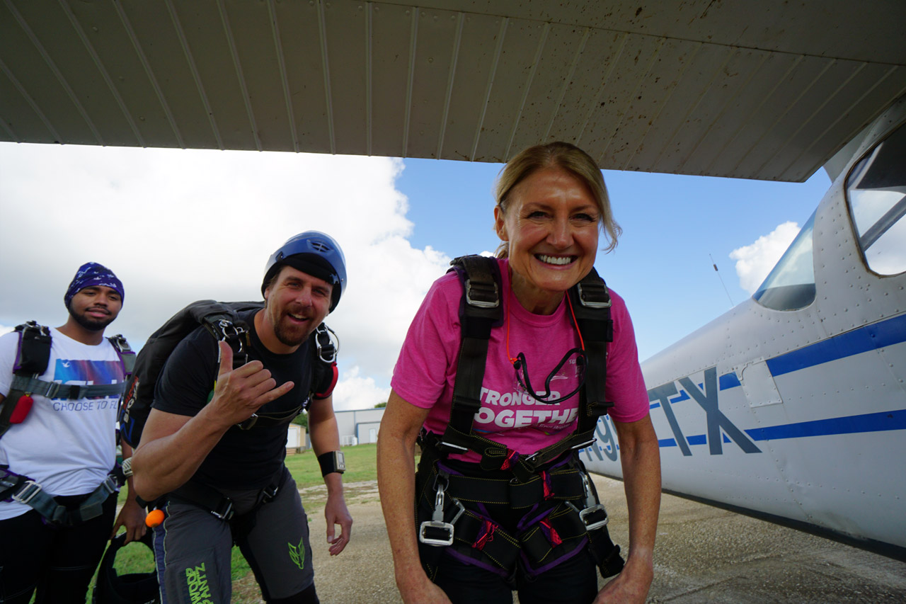 Tandem skydiving student in pink t-shirt getting ready to board airplane for a tandem skydiving at Texas Skydiving near Austin and College Station, TX