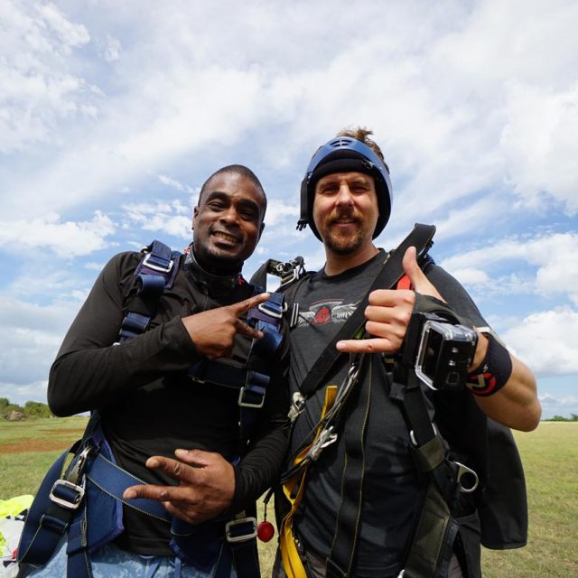 Tandem skydiving student and instructor posing for a photo after landing from a tandem skydive at Texas Skydiving near Austin, TX