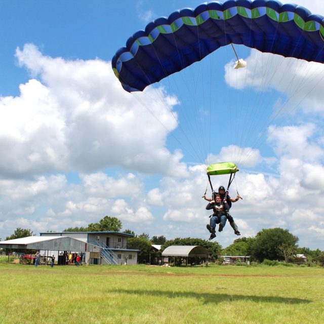 Tandem skydiving student and instructor coming in to and in a grassy field at Texas Skydiving