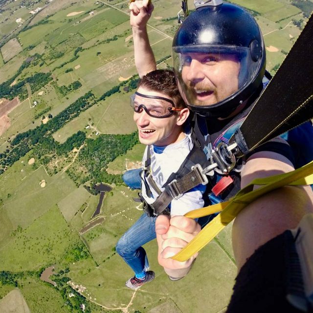 Male tandem skydiving student and instructor under canopy during a tandem skydive at Texas Skydiving near Austin, TX