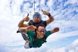 Young man wearing green t-shirt tandem skydiving for the first time at Texas Skydiving near Austin, TX