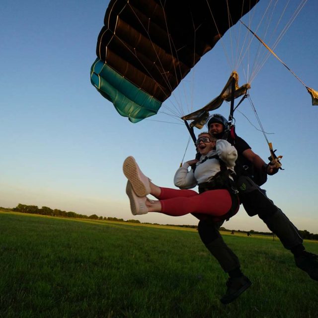 Tandem skydiving student and instructor land in a field at sunset at Texas Skydiving near Austin, TX