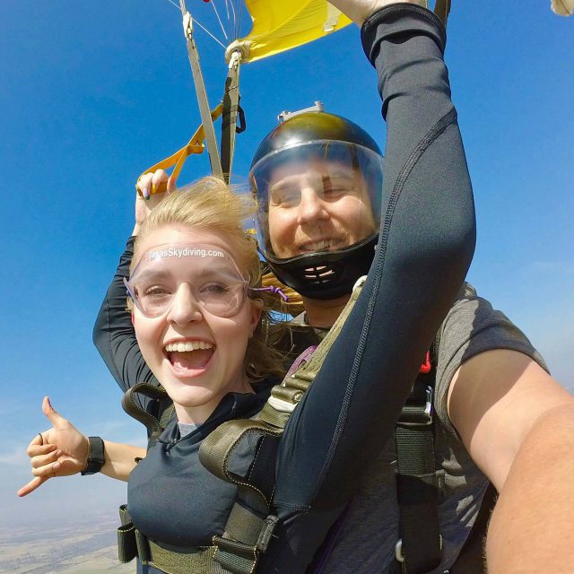 Young blond woman smiles while under canopy during a tandem skydive at Texas Skydiving near College Station, TX
