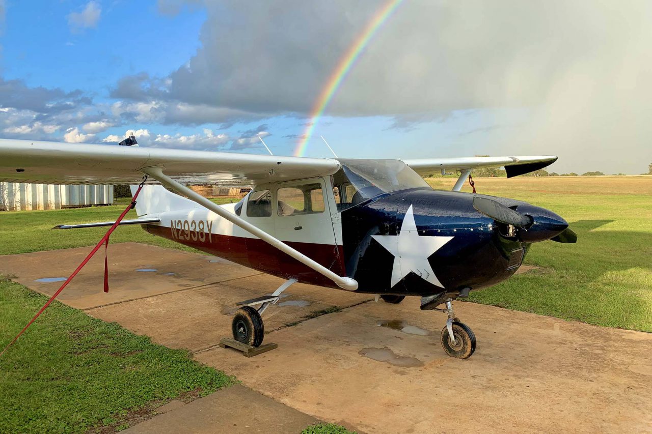 Cessna Airplane with a Texas flag paint scheme sitting on a runway with a rainbow in the background