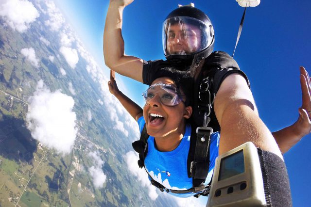 Woman in blue shirt in freefall during a tandem skydive at Texas Skydiving near Austin, TX