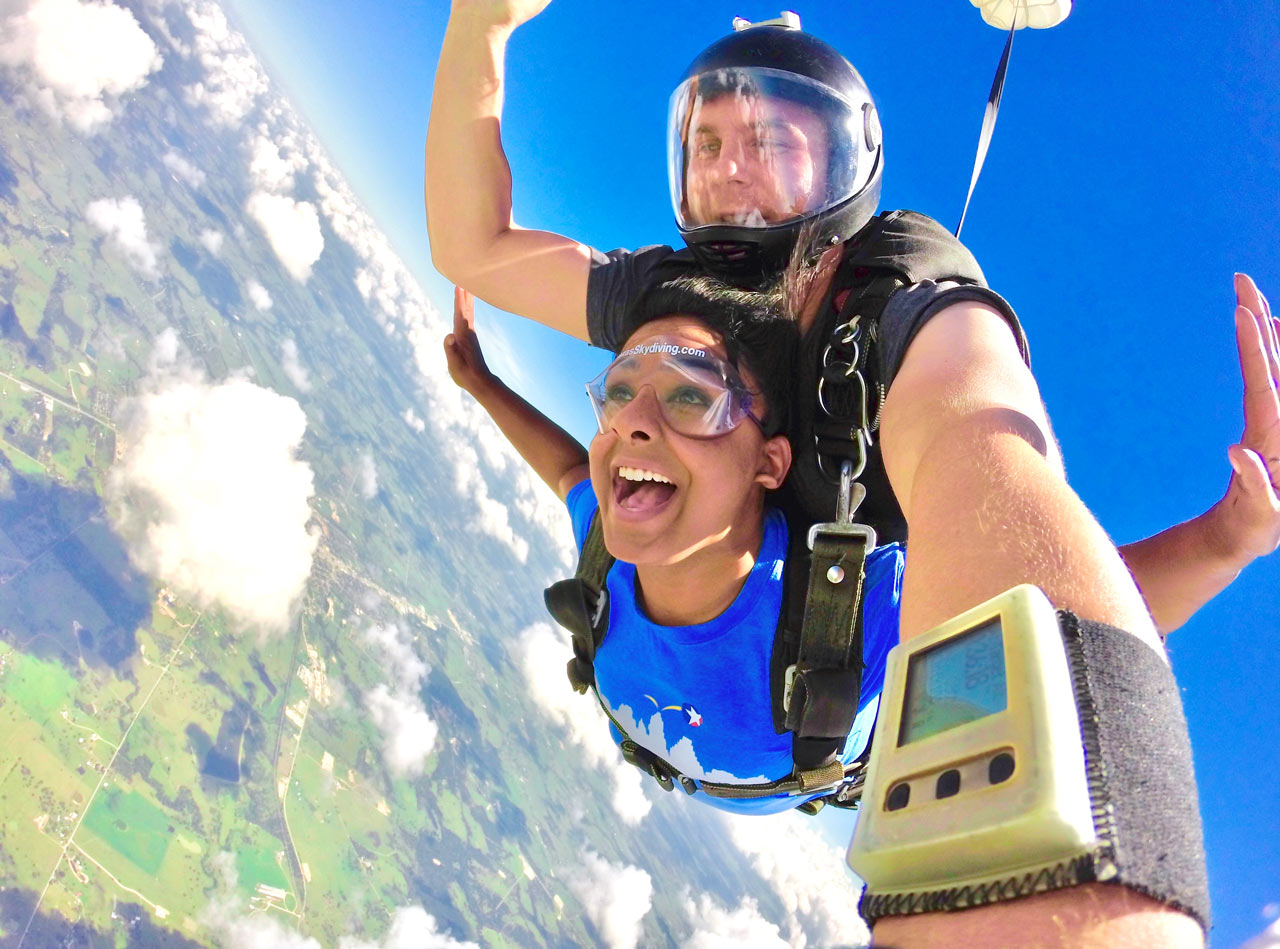 Female tandem skydiving student in freefall wearing a blue t-shirt